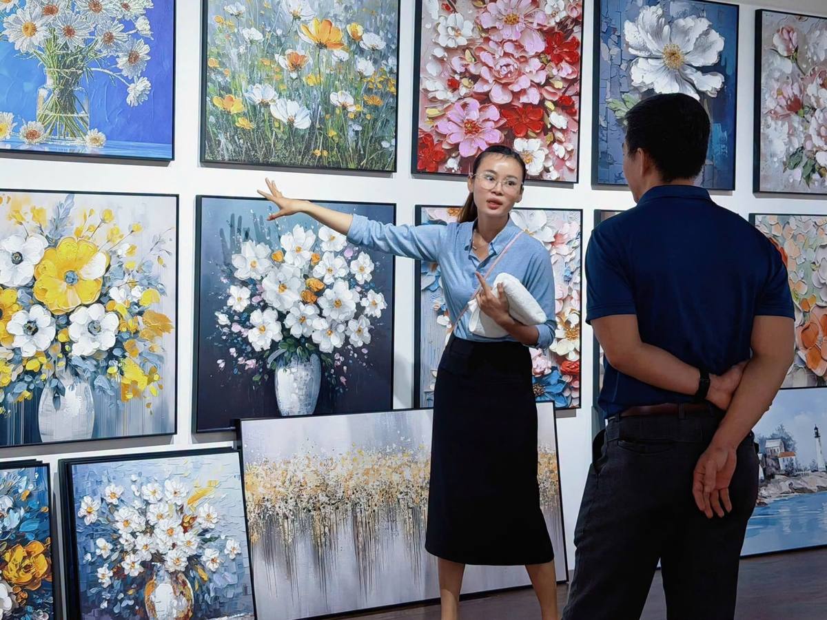 Nhân viên giới thiệu khu trưng bày tranh cho khách tại showroom Tân Phát